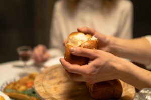 woman's hands breaking a piece of challah at the dinner table