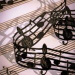 a silk ribbon made of musical notes weaves across a page of sheet music