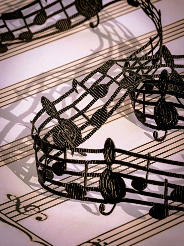 a silk ribbon made of musical notes weaves across a page of sheet music